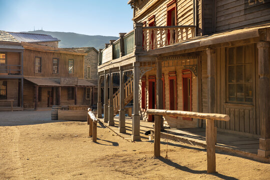 empty street of an old western town with rustic wooden buildings and saloon under a sunny sky