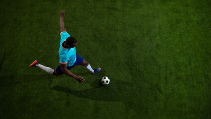 Fototapeta premium Overhead soccer player kicking ball on green field with wide copy space. Concept of football training, tactical sport layout, academy coaching, match preview and gear campaign.