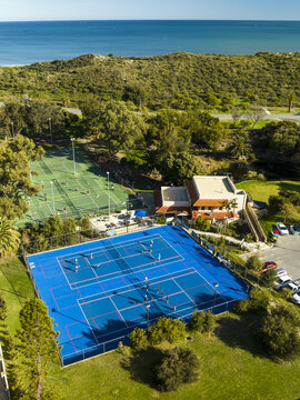 Aerial view of North Shore Community Hub and Cafe featuring tennis courts with people playing near coastal dunes and the Indian Ocean in Kallaroo, Western Australia, Australia.