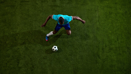 Top view soccer player running toward ball on textured green field. Concept of football movement, match analytics visual, sports training content, pitch strategy and gear promotion. © Lustre Art Group 