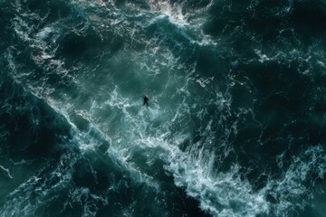 Obraz premium Aerial View of a Lone Person Floating in Turbulent Ocean Waves.
