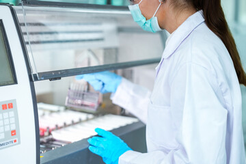Fototapeta premium Medical scientist loading slide rack into automated stainer machine. Lab technician in protective gear processing histology samples in sterile hospital laboratory.