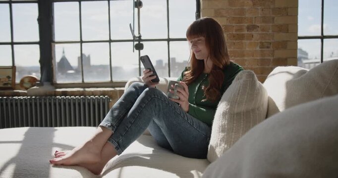 Woman enjoying her Smartphone in sunlight on Sofa using Banking app