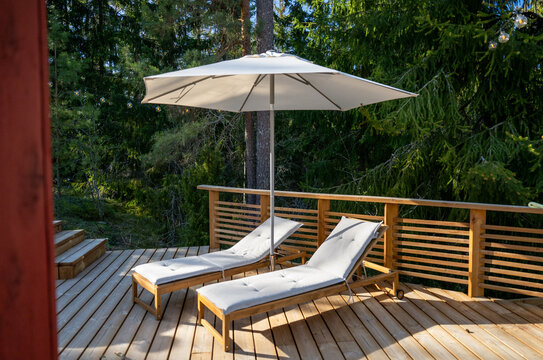 luxury outdoor lounge chairs on wooden terrace with umbrella in forest retreat relaxation vacation concept