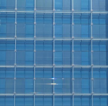 Fondo con vista de cerca de fachada moderna de edificio de oficinas con paneles de vidrio con marcos met&aacute;licos y reflejos