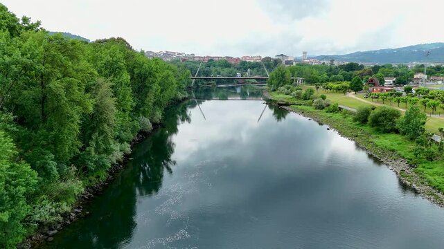 Aerial view flying over mino river towards modern bridge