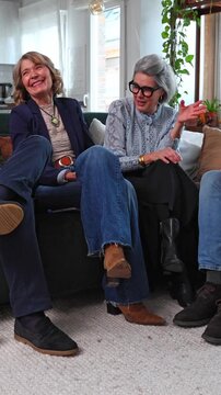 Group of senior friends laughing and talking together at home
