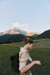 Fototapeta premium Woman hiking in an alpine meadow with a backpack, mountain backdrop, and clear blue sky, showcasing outdoor lifestyle, adventure, wellness, and fresh air, and inspiration.