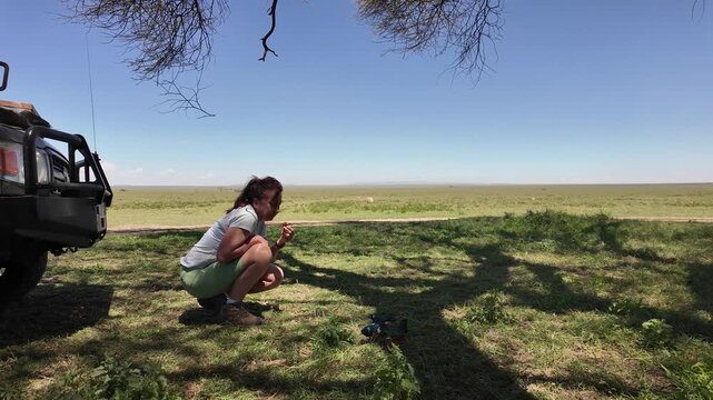 Woman Feeding Colorful Birds Beside a Jeep in the Serengeti &ndash; Tanzania