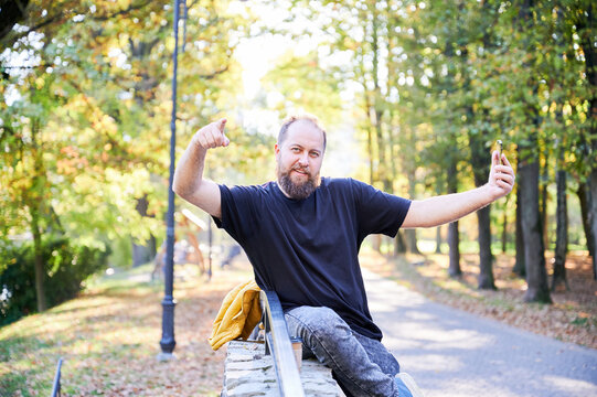 Casual man displays selfassured pose outdoors. Individual with beard strikes confident pose in outdoor setting. Selfassured bearded man captures influential image along scenic park pathway