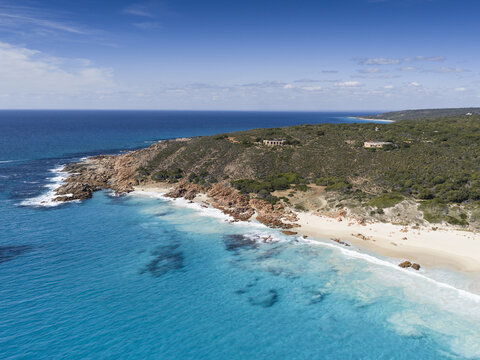 Aerial view of Bunker Bay Beach with turquoise waves crashing against white sand and rocky cliffs under a clear sky Naturaliste, Western Australia, Australia.