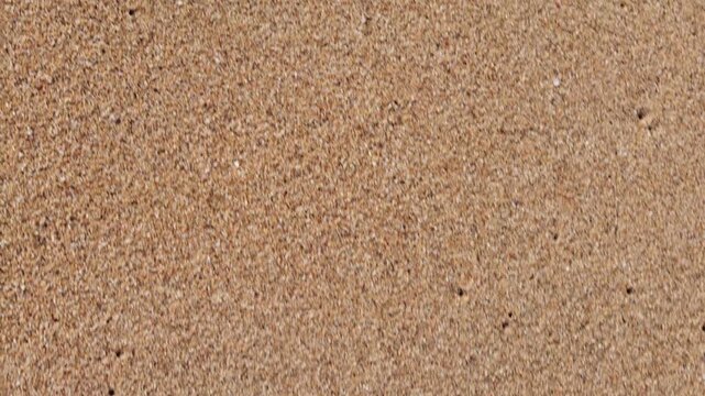 Close-up background of white sand texture on a beach, showing natural patterns and fine grain details.