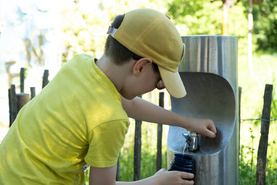 A boy pours water into a bottle from from drinking fountain in Austria