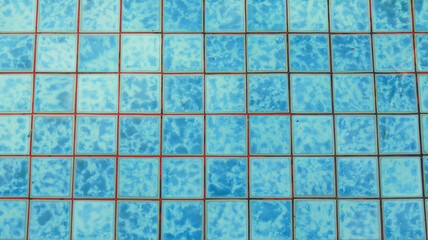 Plakat Top view of blue and turquoise swimming pool mosaic tiles with a textured, marbled finish. The square ceramic tiles are submerged under clear water, creating a clean and refreshing background pattern