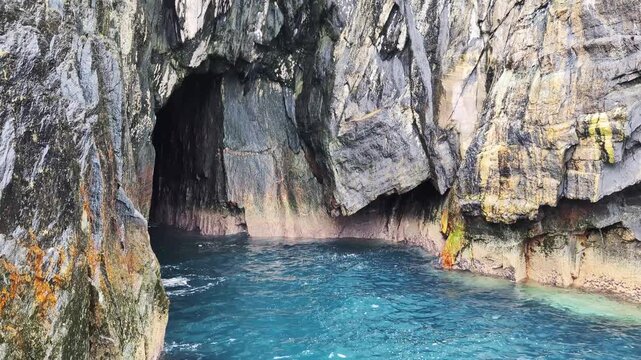 Exploring a rocky coastline with cave with clear blue water on Skellig Michael island, Ireland