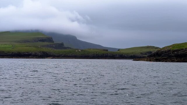 Scenic coastal view on the way to Skellig Michael island. Green irish hills and cloudy sky over calm waters in a remote location of Kerry country