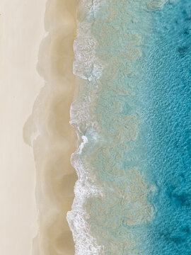 Aerial view of Bunker Bay Beach with turquoise water and white waves washing over golden sand in Naturaliste, Western Australia, Australia.