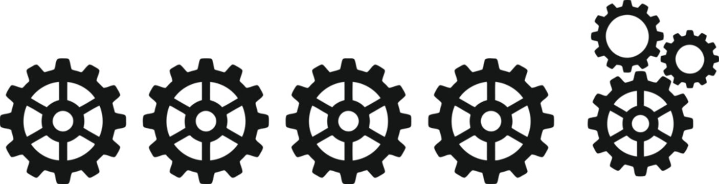 Group of five black gears and cogwheels, including a set of three interlocked for mechanical concepts.