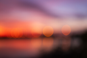 Abstract bokeh lights of sunset over the water with film grain texture,A beautiful abstract background featuring soft orange and yellow bokeh lights shimmering over a calm water surface during twiligh © banjongseal324