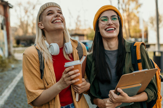 Diverse female students laughing walking on campus