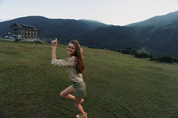 Naklejka premium Happy woman outdoors posing on green grass field with mountains in background casual outfit natural light smiling joyful lifestyle summer day