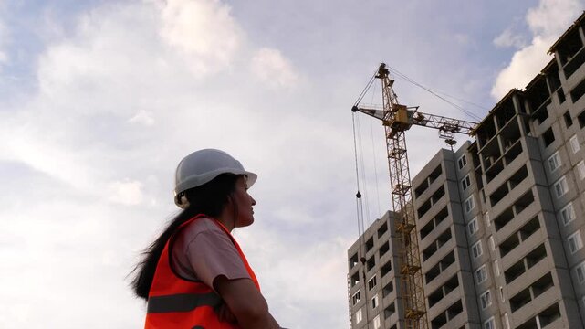Female construction supervisor in safety helmet monitoring building site at sunset. Concept of women in construction, leadership and project management, engineering industry and modern workforce.
