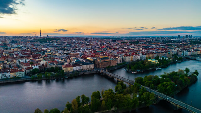 Aerial view of the historic city skyline featuring the Vltava River, National Theatre, and Legion Bridge under a sunset sky in Prague, Prague, Czechia.