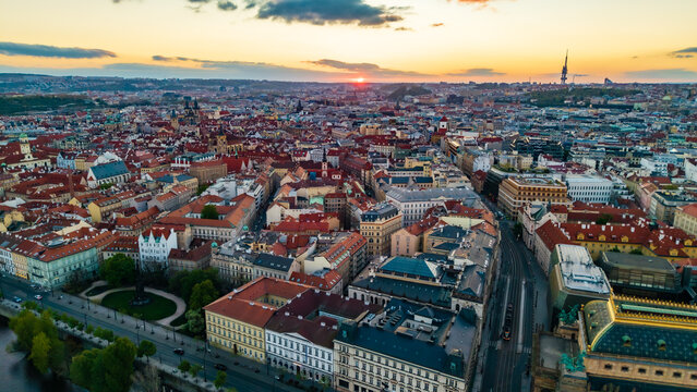 Aerial view of the historic Old Town rooftops and the Zizkov Television Tower during a vibrant sunset in Prague, Prague, Czechia.