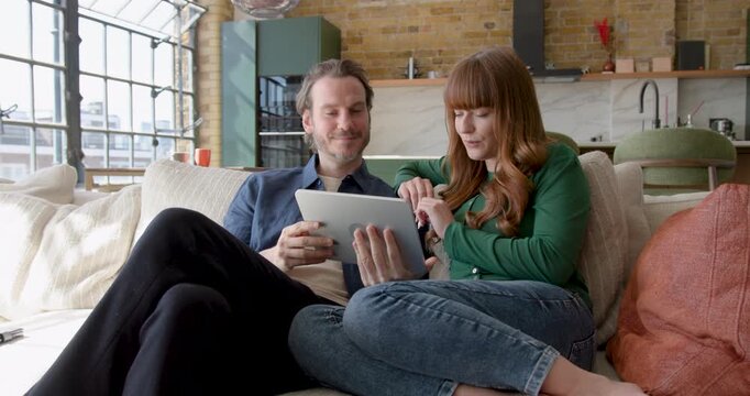 Couple Collaborating Over Digital tablet, Looking at Home Finances