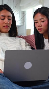 Two shocked young women reading bad news online on a laptop