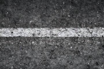 Fototapeta premium Rough Asphalt Surface White Painted Line Horizontal Coarse Texture Stones Cracks Urban Road Infrastructure Background