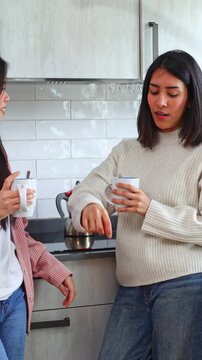 Two female friends talking over coffee in the kitchen