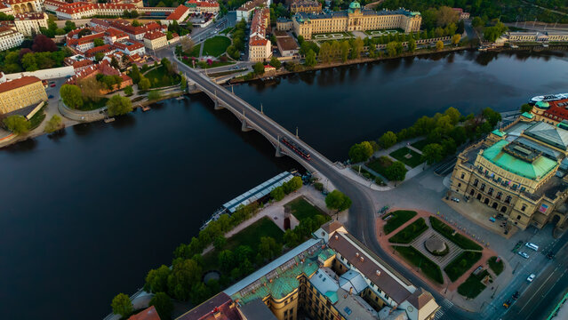 Aerial view of the Manes Bridge crossing the Vltava River with the Rudolfinum and historic architecture under soft evening light in Prague, Prague, Czechia.