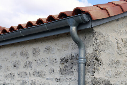 Goutti&egrave;re zinc gris sur la fa&ccedil;ade de la maison, descentes rondes sur la fa&ccedil;ade en pierre