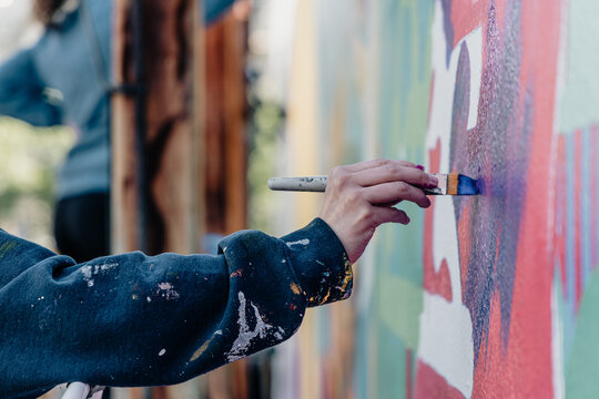 A Hand Painting with a Brush on a Wall