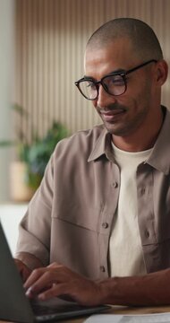 Happy man, typing and creative with laptop in office, online and scriptwriter with glasses for story. Screenplay, research and person with smile for draft, publication and media project on website