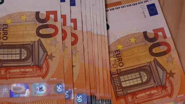 Close-up view of fifty euro banknotes stacked together on wooden surface