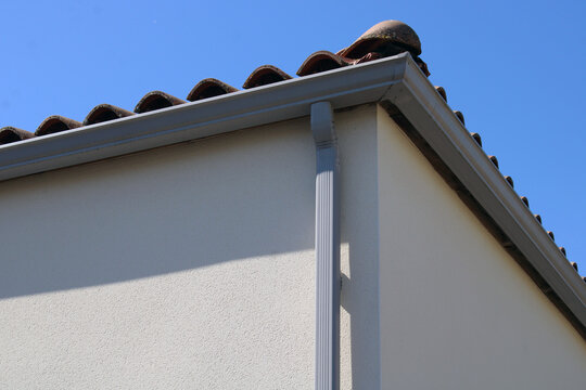 Goutti&egrave;re rectangulaire avec descente en aluminium de forme rectangulaire couleur grise, install&eacute;e sur la fa&ccedil;ade d&rsquo;une maison.