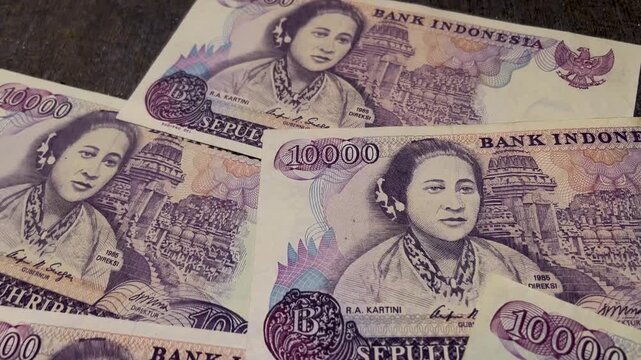 Close up video of a collection of vintage Indonesian 10000 rupiah banknotes dated 1985, featuring the portrait of R A Kartini.