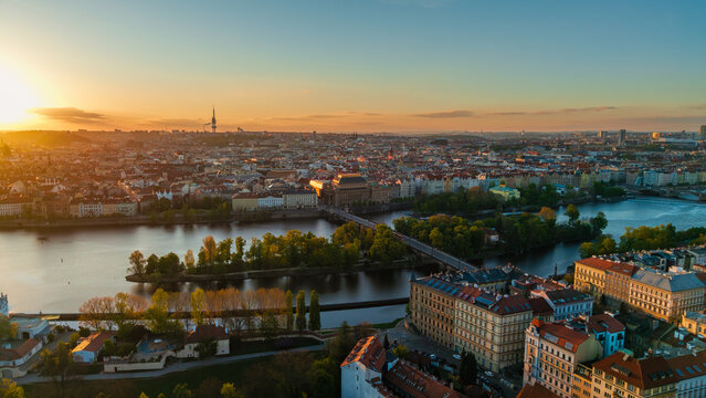 Aerial view of the Vltava River and historic skyline during golden hour sunset with bridges and lush greenery in Prague, Prague, Czechia.