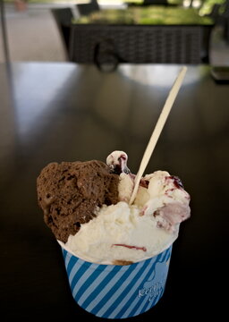 Coppetta di gelato artigianale con gusti misti servita su un tavolo, atmosfera da caff&egrave; all&rsquo;aperto