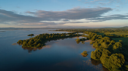 Obraz premium Aerial View of Serene Lake and Lush Green Forest During Golden Hour, Calm Waters Reflecting Sky, Beautiful Nature Landscape at Sunset