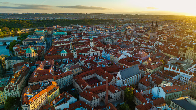 Aerial view of the historic Old Town with its iconic red rooftops, ancient churches, and the Vltava river during a golden sunset in Prague, Prague, Czechia.