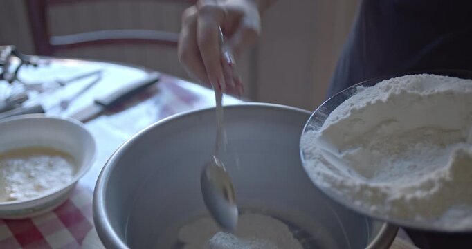 Watch as flour is carefully added to a mixing bowl, an essential step in preparing delicious homemade baked goods. Perfect for cooking and recipe content.