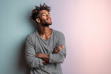 Fototapeta premium Portrait of a blissful man in his 20s with arms crossed in pastel or soft colors background