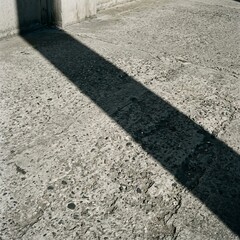 Fototapeta premium Long Shadow Cast Across Textured Concrete Surface.