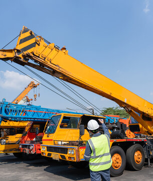 Crane safety inspection mobile crane construction engineer worker hard hat reflective vest coordinating crane safety inspection construction yard