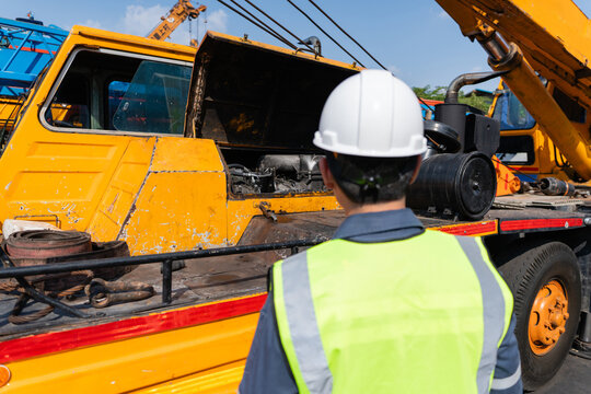 Crane safety inspection mechanic truck maintenance Worker hard hat during crane safety inspection beside service truck with open engine bay