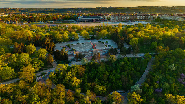 Aerial view of the Prague Metronome in Letna Park surrounded by lush green trees and the city skyline during golden hour in Prague, Prague, Czechia.