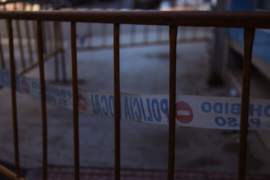 Temporary fencing and barricade tape with policia local and prohibido el paso texts on a city street, indicating restricted access or a secured area for public safety